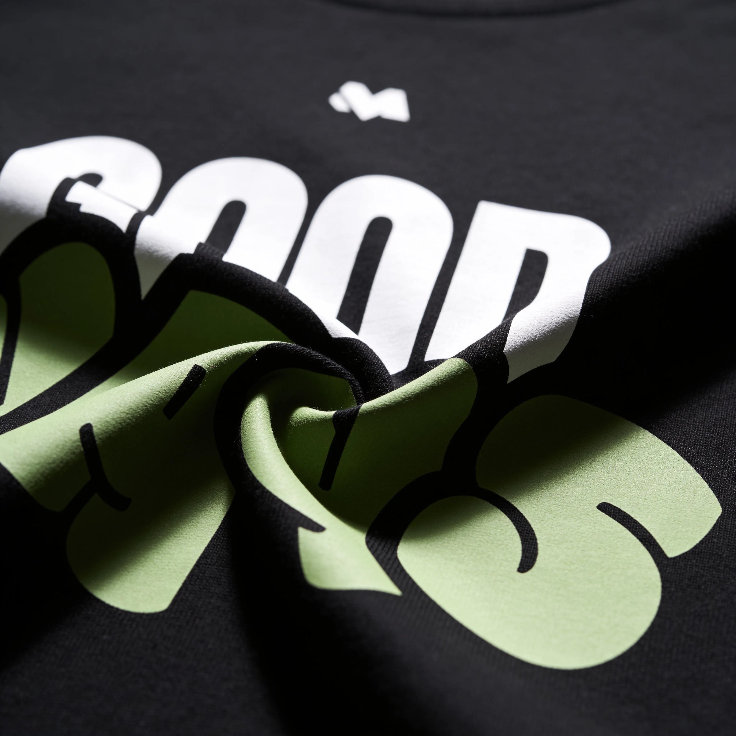 Close-up of the Good Ways print showing sage green bubble letters and white type on 180 GSM black organic cotton