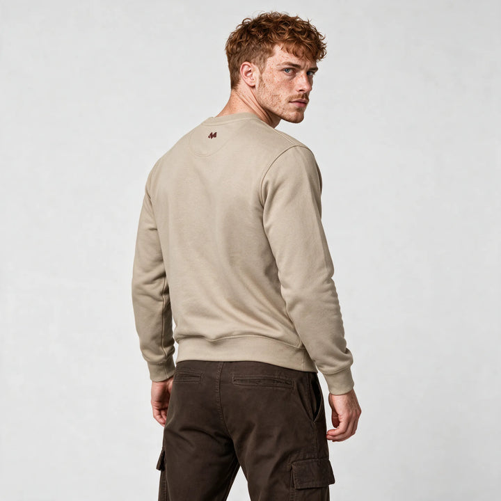 Side-back view of the beige sweatshirt with a small logo below the collar