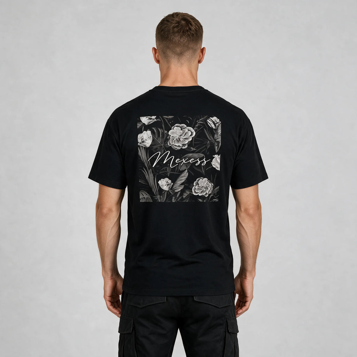 Back view of the black t-shirt with a framed black-and-white floral print and MEXESS script