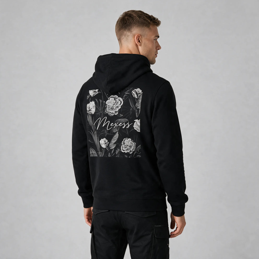 Man wearing the black floral hoodie, three-quarter back view showing the square flower print