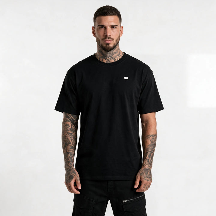 Model in a black organic cotton t-shirt with a small white MEXESS logo on the left chest, front view