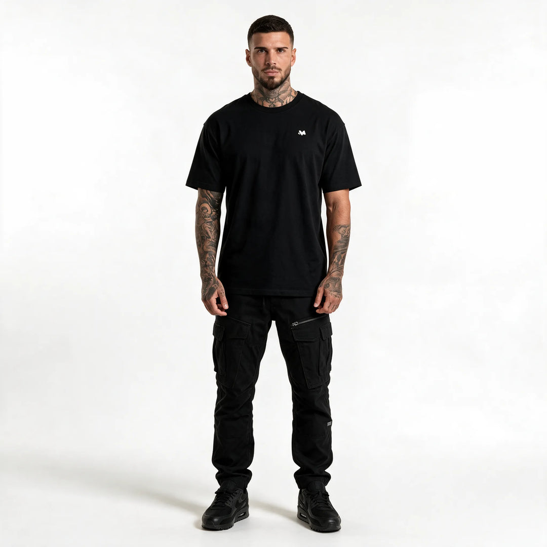 Full-length front view of a man in a black t-shirt with a small chest logo and black trousers