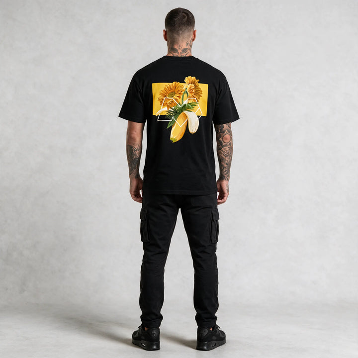 Full-length back view of a black t-shirt with a gerbera and banana graphic print