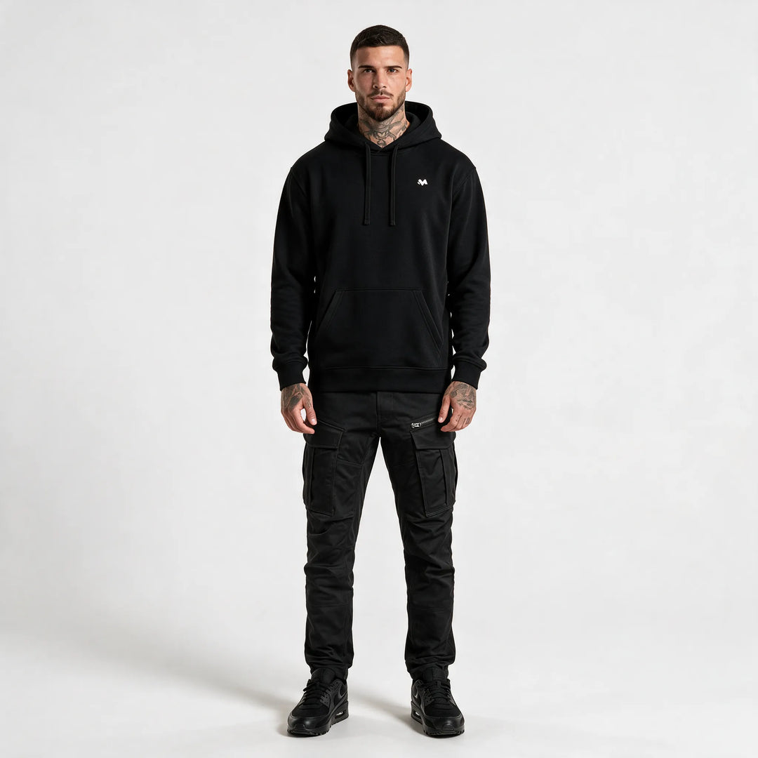 Full-length front view of a man in a black hoodie with a front pocket and black trousers