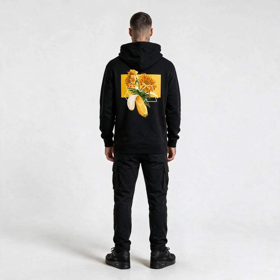 Full-length back view of a black hoodie with a gerbera and banana graphic print