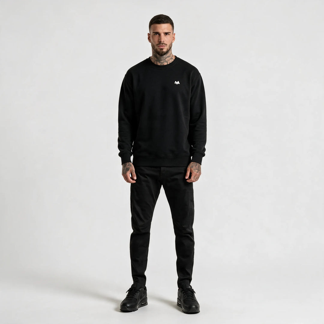 Full-length front view of a man in a black crew neck sweatshirt and black trousers