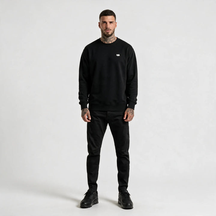 Full-length front view of a man in a black crew neck sweatshirt and black trousers