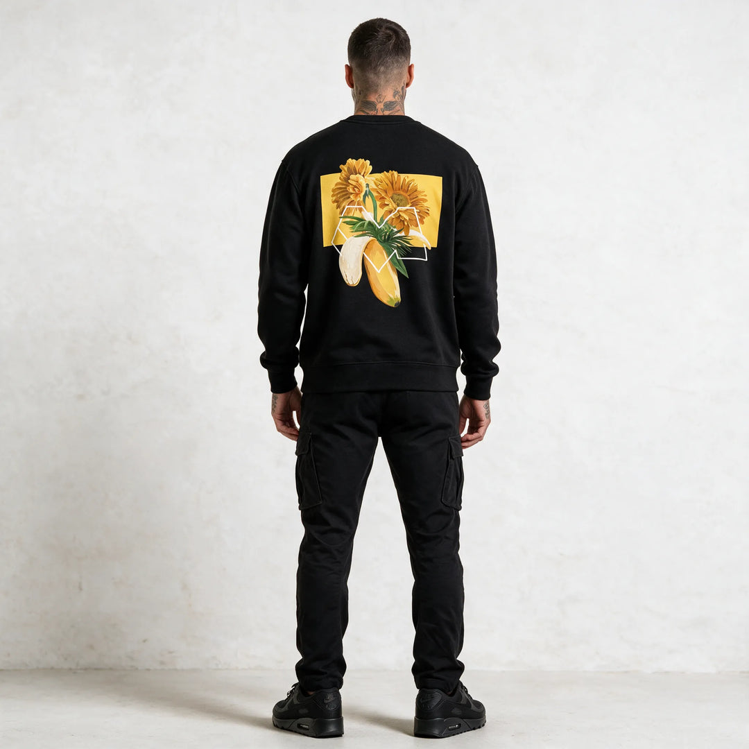 Full-length back view of a black sweatshirt with a gerbera and banana graphic print