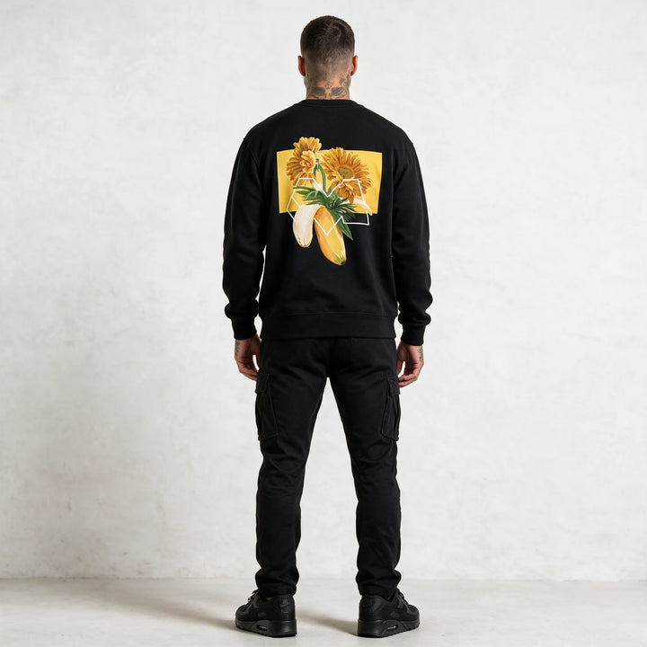 Full-length back view of a black sweatshirt with a gerbera and banana graphic print