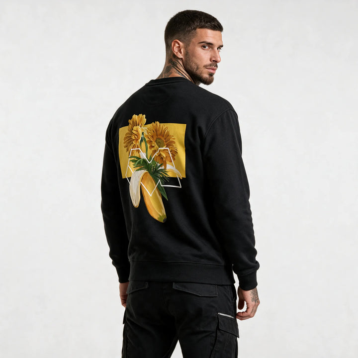 Back of a black banana sweatshirt with orange gerberas, palm leaves and a white M outline on a yellow block