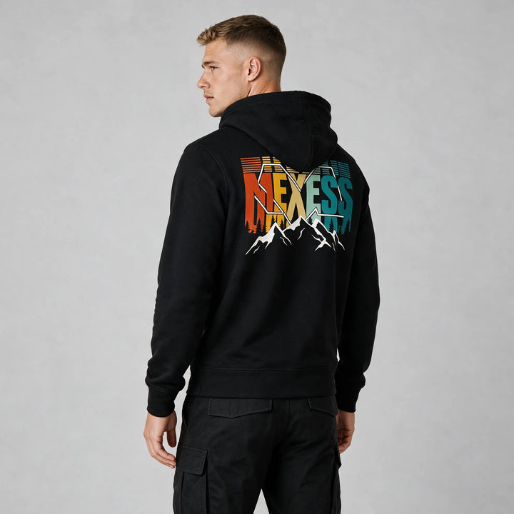 Man in a black graphic hoodie, back view of the MEXESS lettering in orange, yellow, mint and teal below the hood