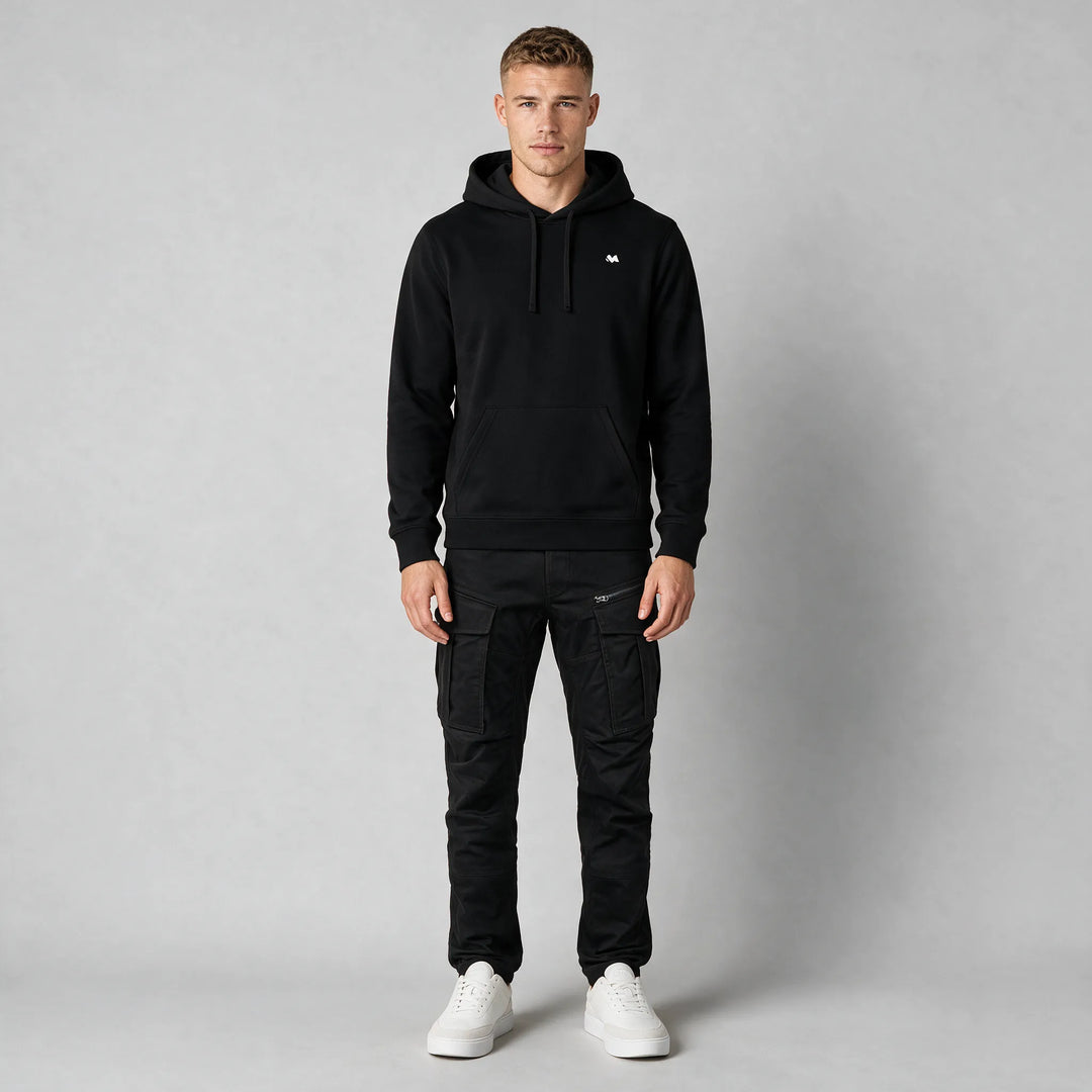 Full-length front view of a black drawstring hoodie worn with black cargo pants and white sneakers