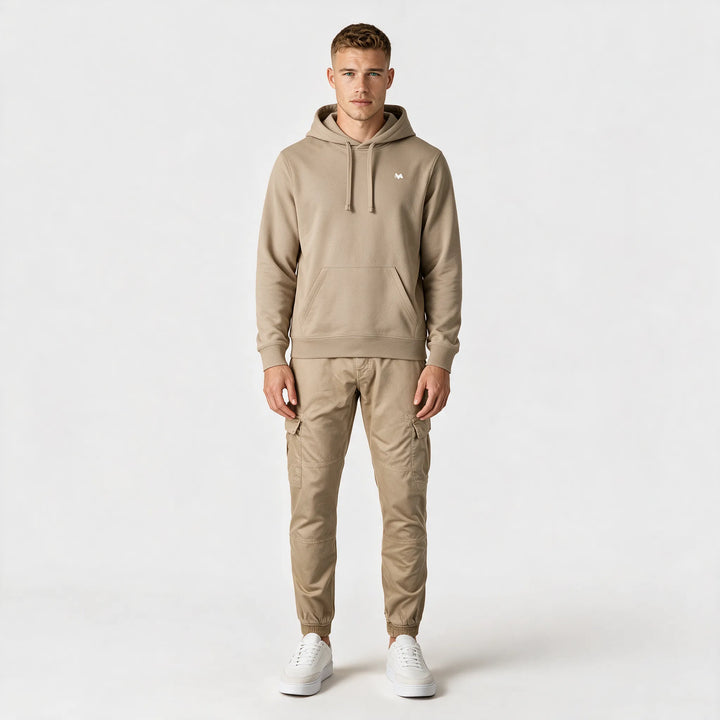 Full-length front view of a beige drawstring hoodie worn with beige cargo pants and white sneakers
