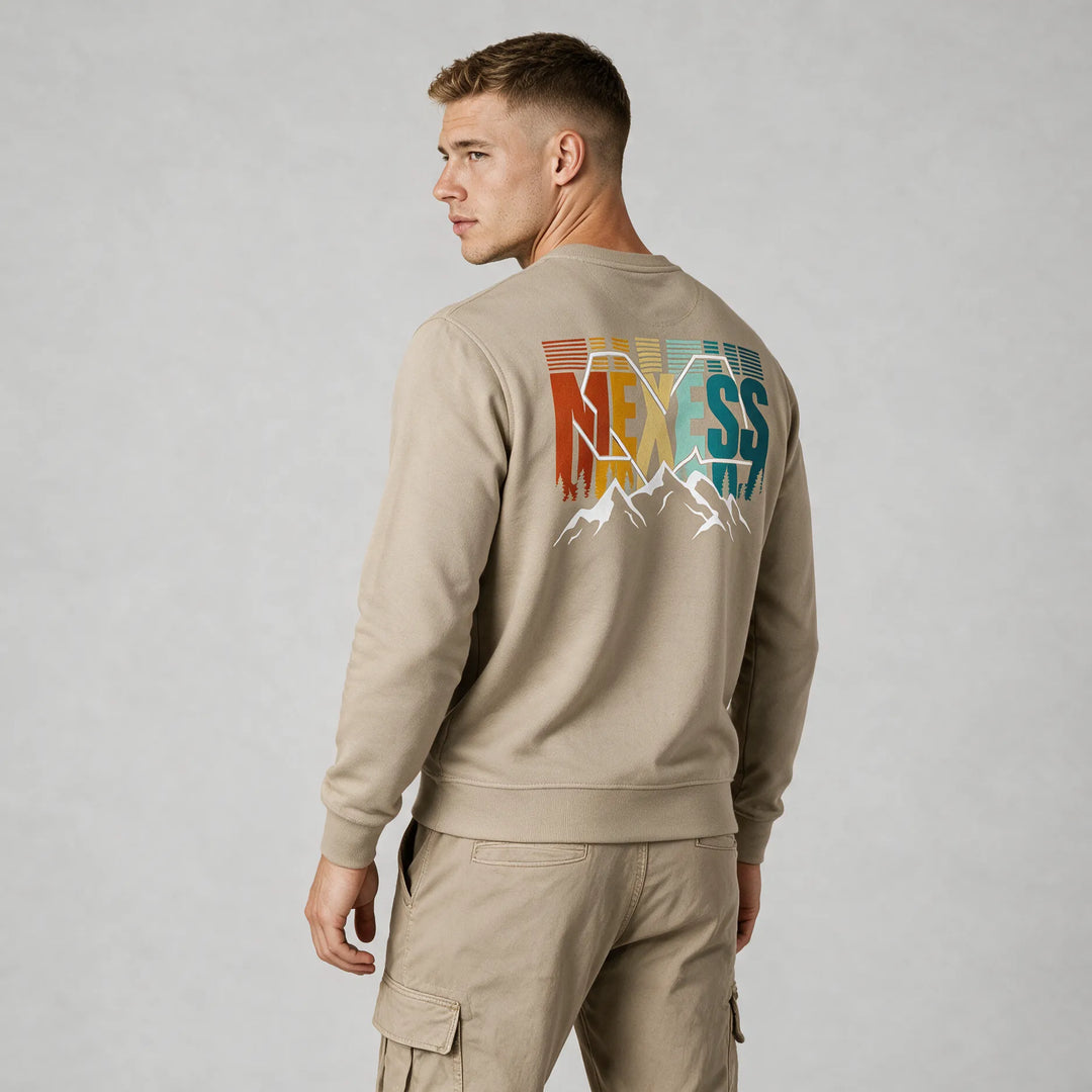 Beige organic cotton crewneck sweatshirt with a retro MEXESS mountain back print, worn by a man, rear three-quarter view