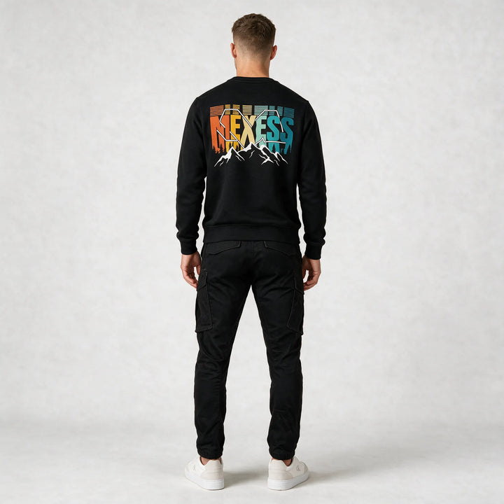 Full-length back view of a black mountain sweatshirt with a large multicolor MEXESS back print and black cargo pants
