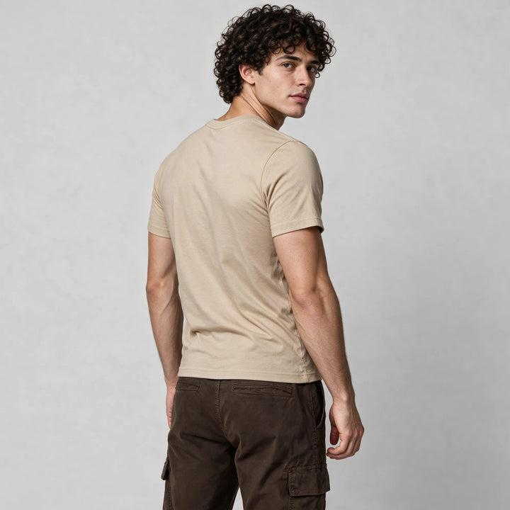 Rear three-quarter view of a man in a beige organic cotton t-shirt with dark brown cargo pants