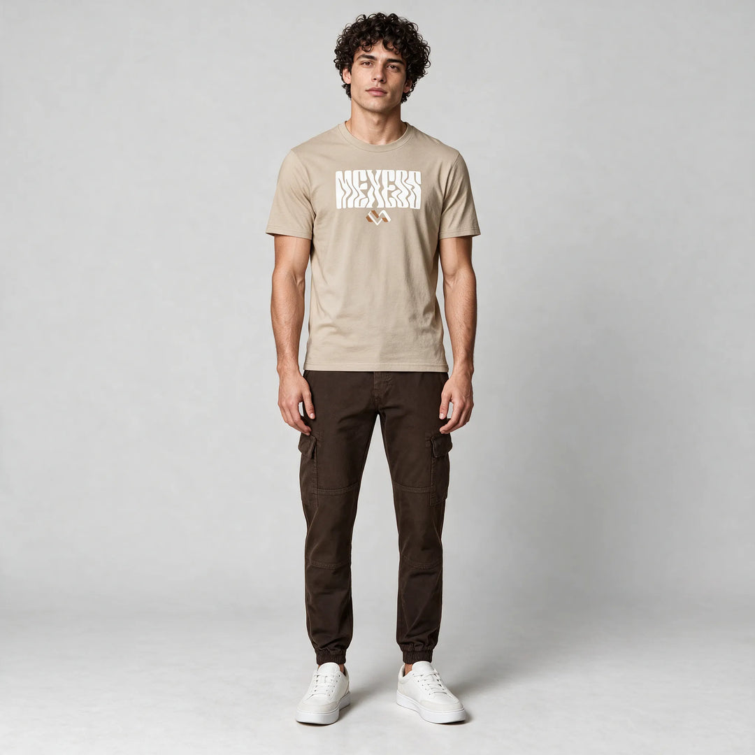 Full-length front view of a beige graphic t-shirt worn with dark brown cargo pants and white sneakers