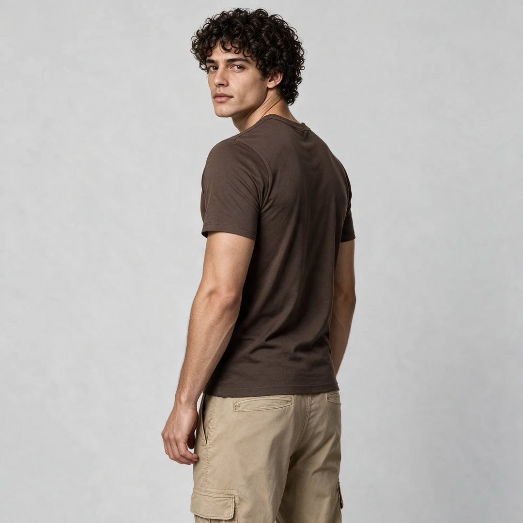 Rear three-quarter view of a man in a mocha brown organic cotton t-shirt with beige cargo pants