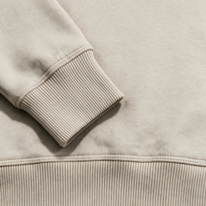 Close-up of the ribbed cuff and hem of the beige organic cotton hoodie
