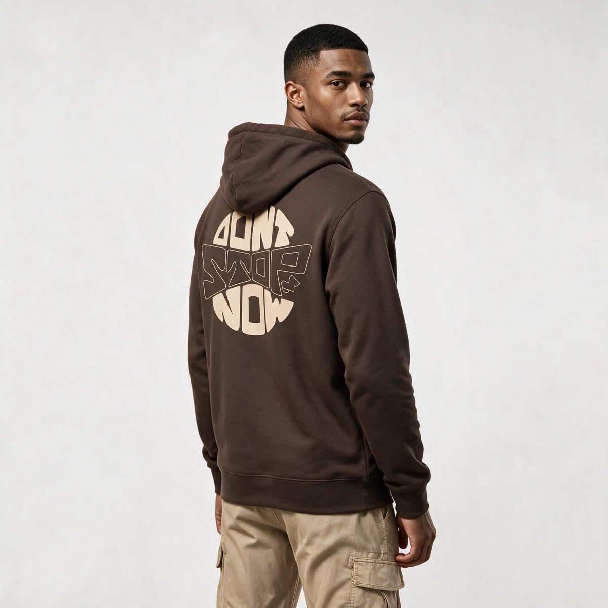 Mocha hoodie, three-quarter back view with a round beige DON'T STOP NOW print