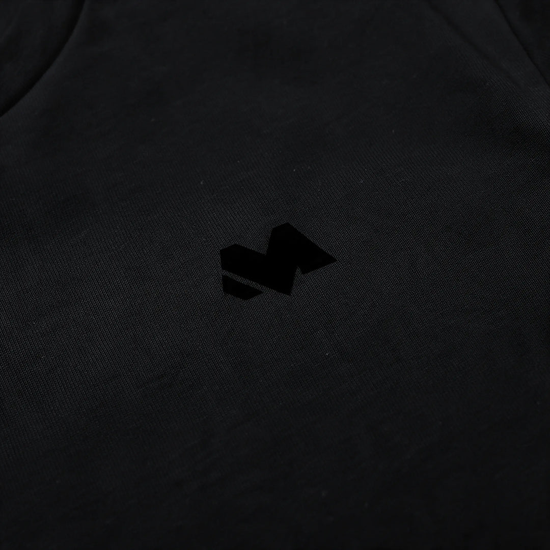 Close-up of the small tonal M logo on the left chest of the black t-shirt